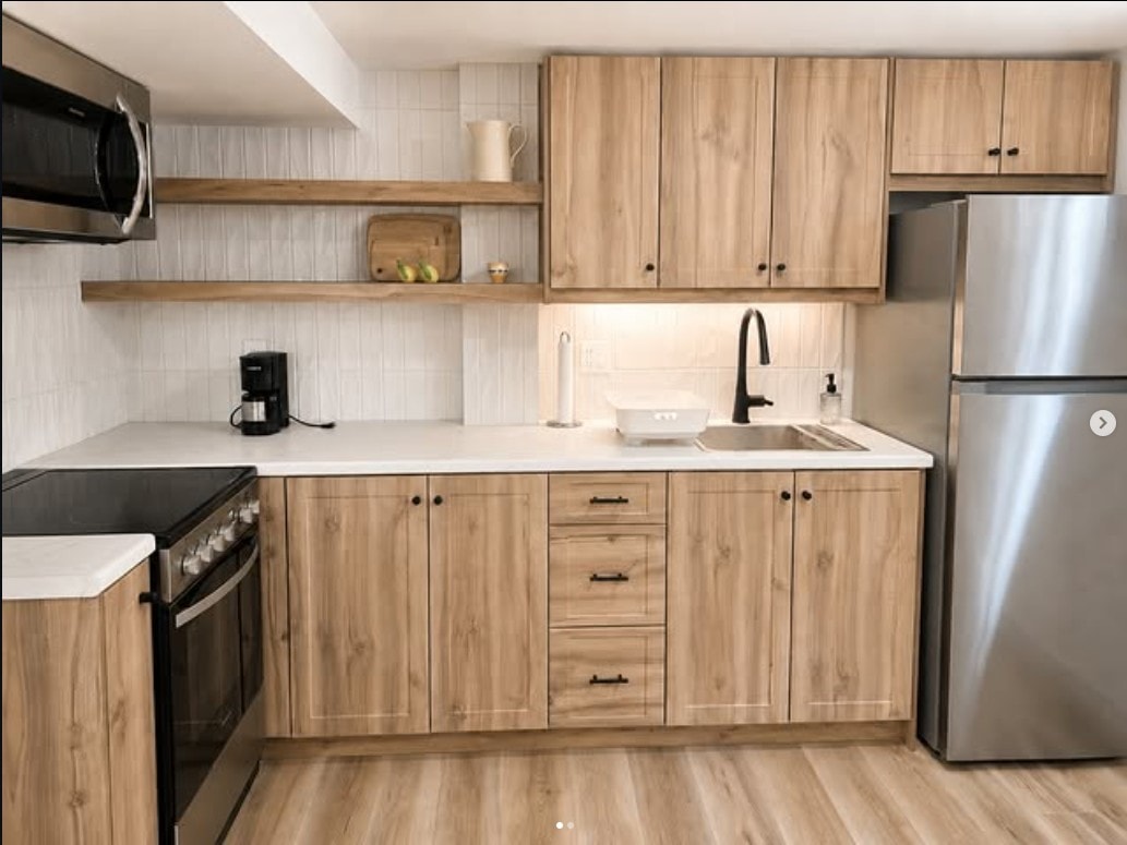Natural wood kitchen with open shelving, white quartz countertops and black handles